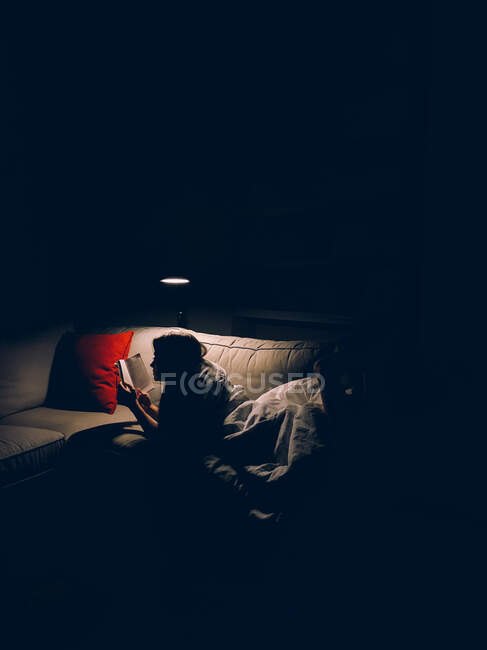 Woman reading a book under the lamp — Stock Photo