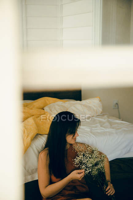 Frau mit Blumen sitzt im Schlafzimmer — Stockfoto