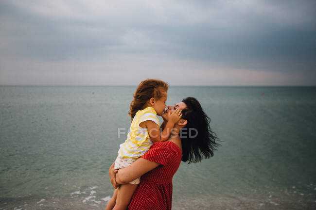 Madre e figlia abbracciare il tempo in riva al mare — Foto stock