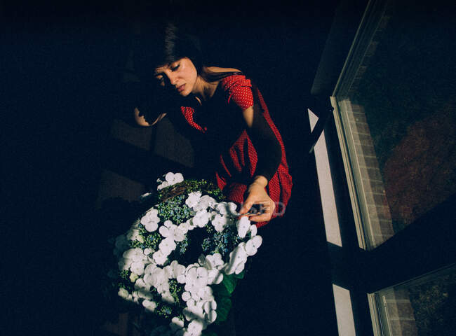 Mulher sentada junto à janela com flores — Fotografia de Stock