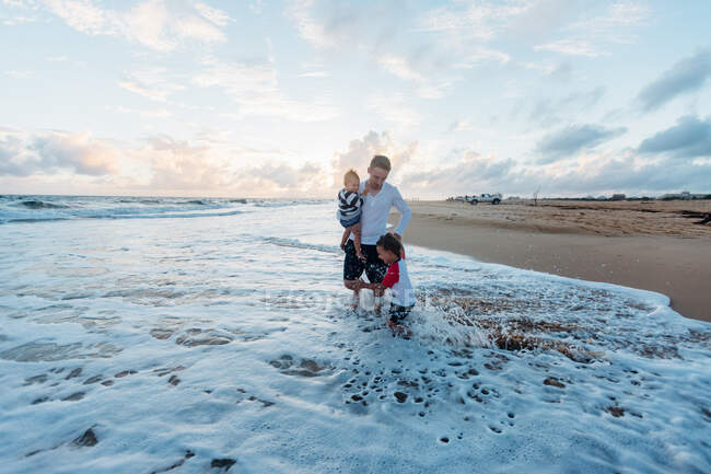 Man with two kids by the ocean — Stock Photo