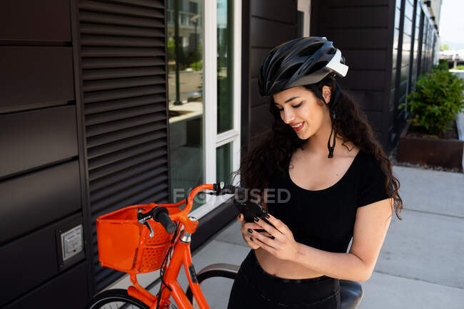 Giovane donna con casco moto e smartphone — Foto stock