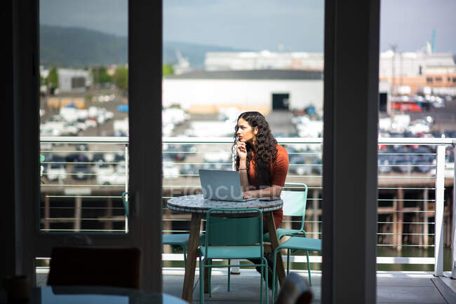 Jeune femme assise à table et utilisant un ordinateur portable et boire du café — Photo de stock