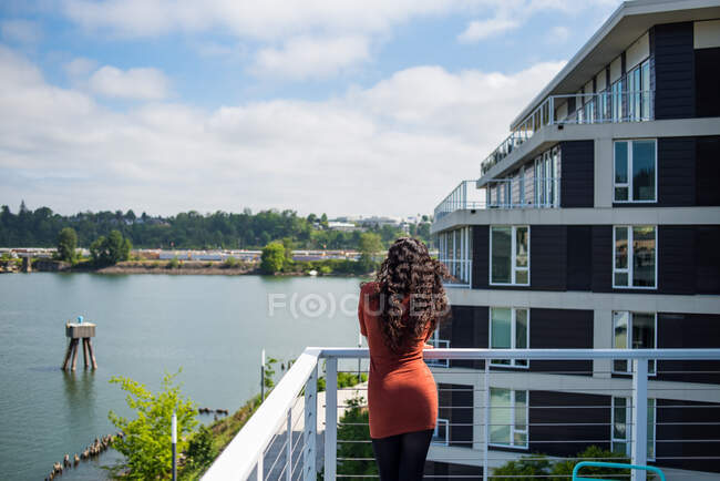 Giovane donna vestita di rosso sul tetto del fiume — Foto stock