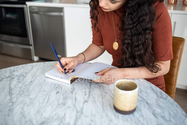 Frau schreibt an Notizbuch und liest Buch im Café — Stockfoto