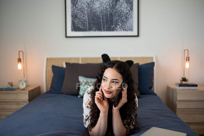 Schöne junge Frau mit Katze, die auf dem Bett liegt und in die Kamera schaut — Stockfoto