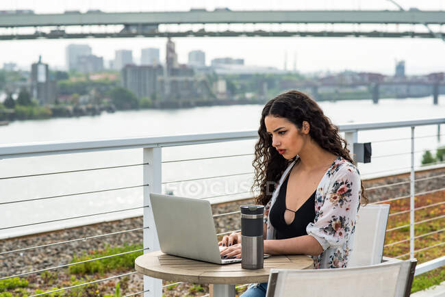 Молода жінка сидить на лавці і використовує ноутбук — стокове фото