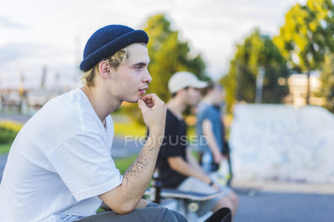 Молодий ковзаняр на скейтпарк використовує свій смартфон влітку, Монреаль, Квебек, Канада. — стокове фото