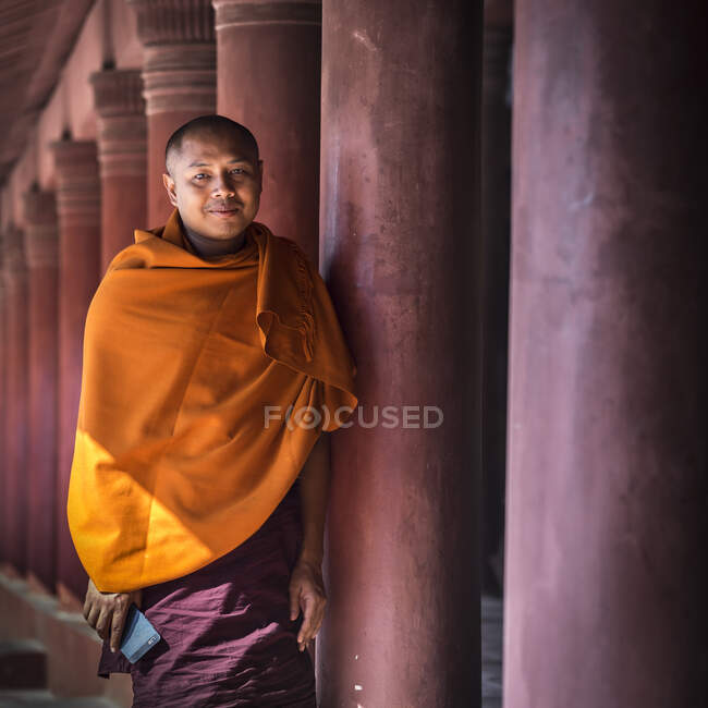 Portrait d'un moine bouddhiste vêtu d'une robe orange tenant une foule — Photo de stock