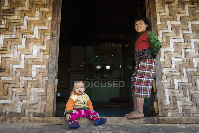 Due ragazzi alle porte della loro casa con pareti di bambù, Hsipaw, H — Foto stock