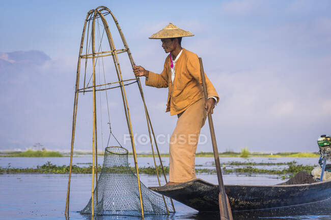 Vue latérale du pêcheur Intha avec pêche conique traditionnelle ne — Photo de stock