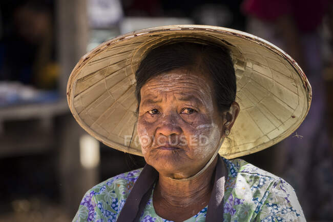 Portrait of adult woman with conical hat at street market in village — Stock Photo