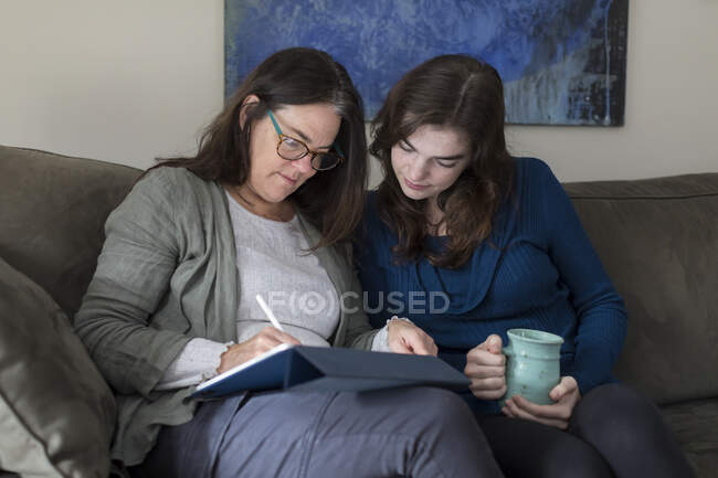 Mutter und Tochter arbeiten gemeinsam an einem Tablet — Stockfoto
