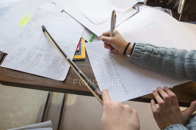 Close-up of two children drawing a holiday music program on paper — Stock Photo