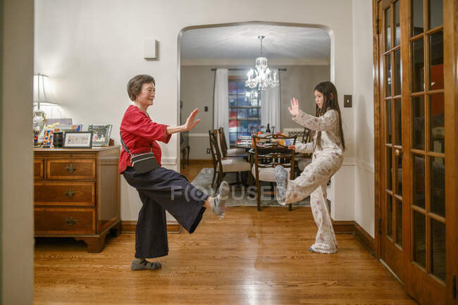 A grandmother teaches her tween granddaughter tai chi at home — Stock Photo