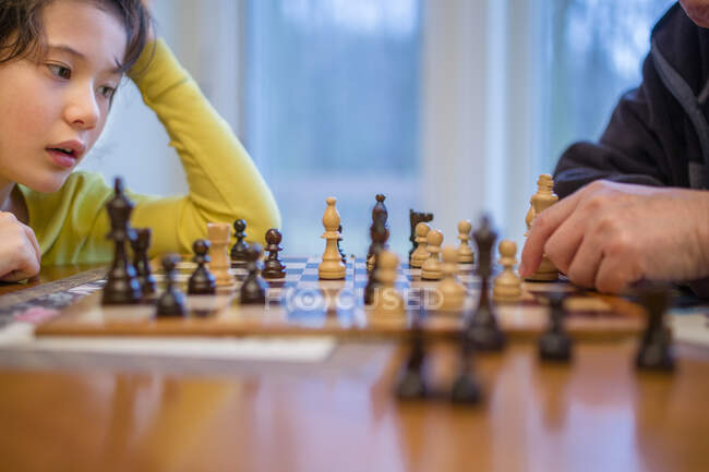 Close-up of a boy leaning over a chessboard studying his next move — Stock Photo