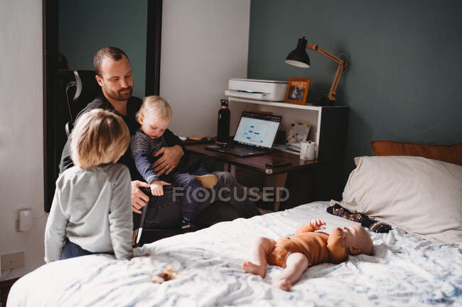 Kids on top of dad who is trying to work while from home during covid — Stock Photo
