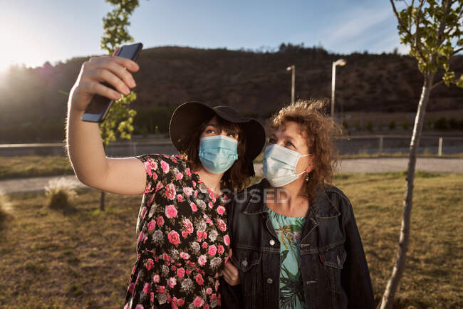 A Latina mother and daughter take a selfie photo with a cell phone and — Stock Photo