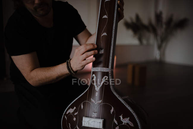 A man playing a tanpura in dark room — Stock Photo