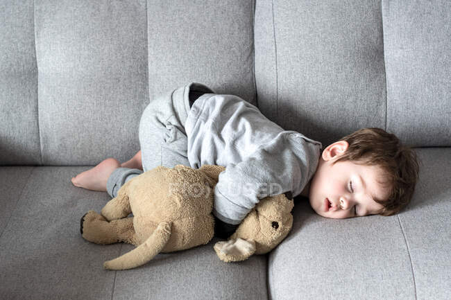 Criança pequena dormindo no sofá em uma postura estranha. — Fotografia de Stock