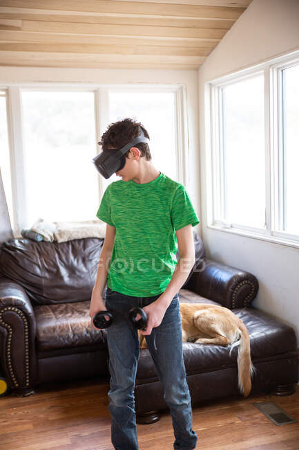 Teen boy playing with VR system with family dog behind him on couch — Stock Photo