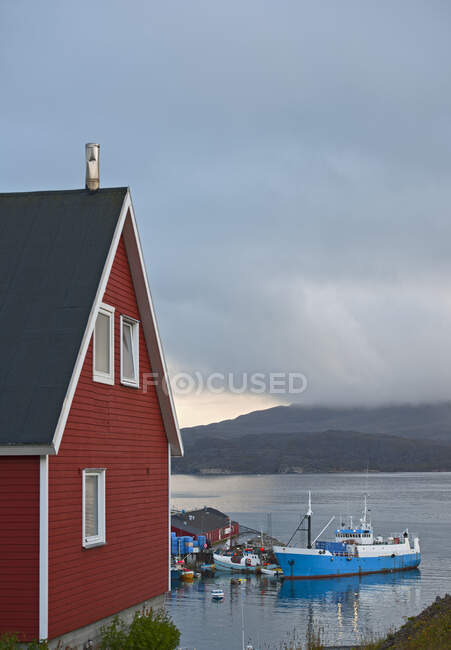 Scatto panoramico di edificio rosso in legno sulla riva del lago in una giornata nuvolosa — Foto stock