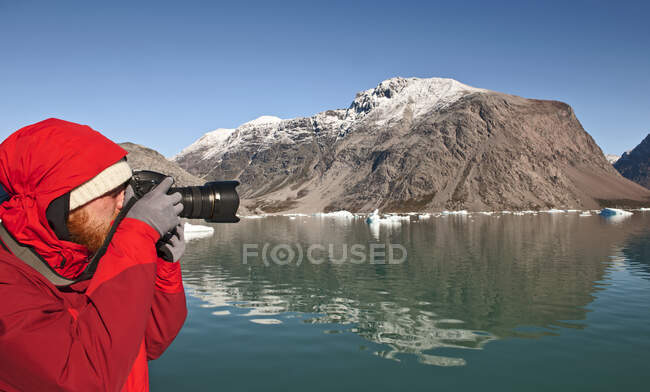 Homme prenant des photos avec un appareil photo reflex numérique dans le sud du Groenland — Photo de stock