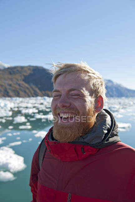 Блондин с бородой смеется над фьордом на юге Гренландии — стоковое фото