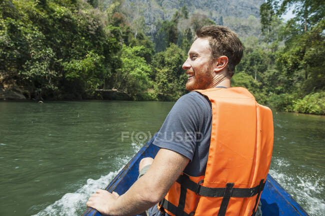 Young man enjoying a ride on a long tail boat in Laos — Stock Photo