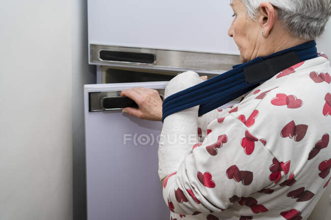 Donna anziana dai capelli bianchi caucasici con braccio rotto con benda bianca — Foto stock