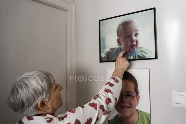 Grand-mère avec bras cassé regardant des photos de son petit-fils — Photo de stock
