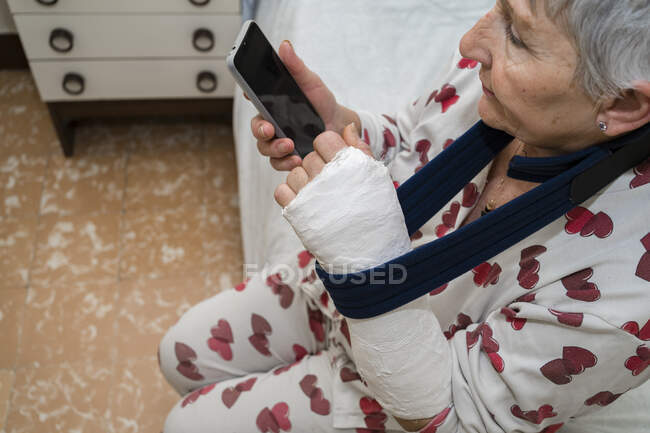 Donna anziana caucasica con i capelli bianchi con braccio rotto seduta — Foto stock