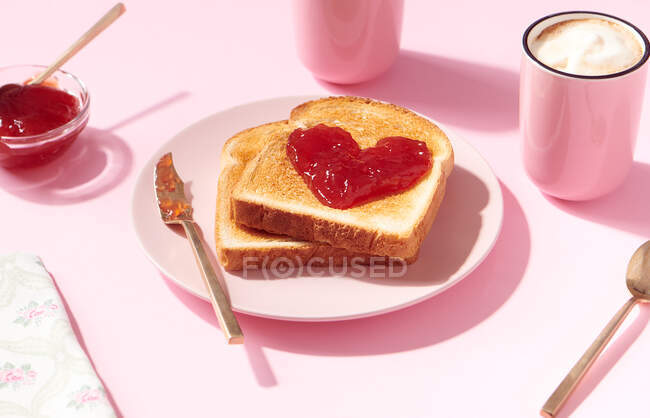 Toasts mit herzförmiger Erdbeermarmelade darauf als Konzept für Liebe und Valentinstag — Stockfoto