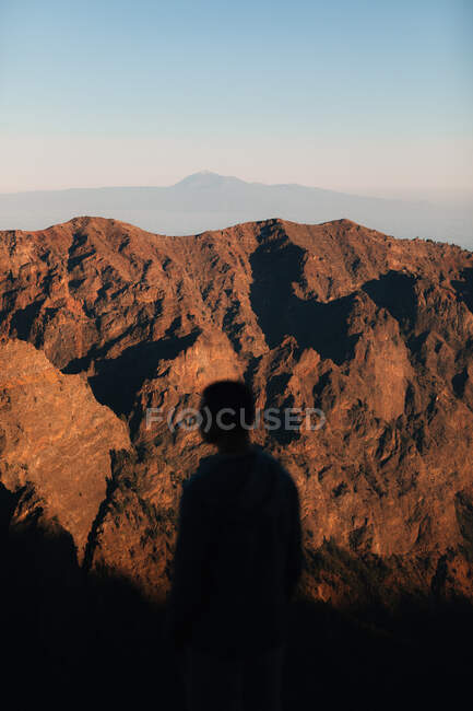 Чоловік дивиться на скелясті гори під час заходу сонця — стокове фото