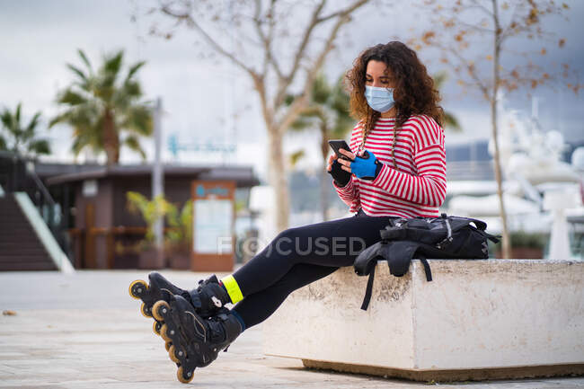 Жінка в роликових лопатях за допомогою смартфона на порожній вулиці — стокове фото
