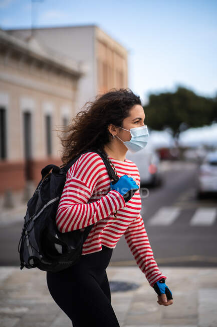 Jeune femme masquée marchant dans la rue — Photo de stock