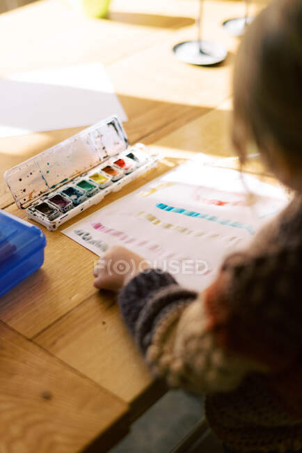 Petite peinture de fille préscolaire avec aquarelles à la table de cuisine — Photo de stock