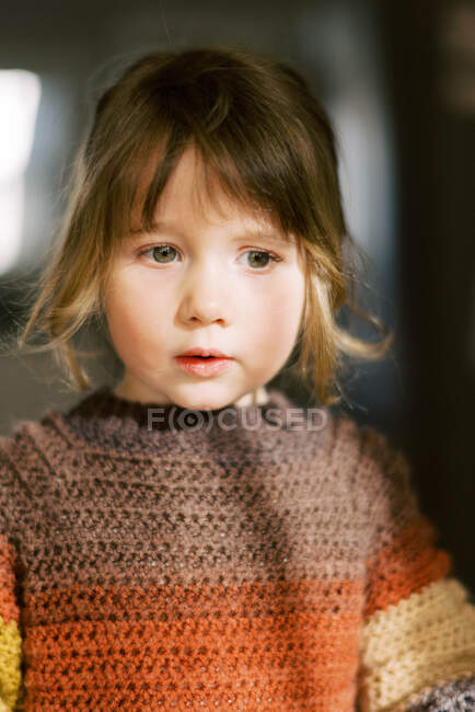 Милая девочка дошкольного возраста выглядит сосредоточенной, как в мыслях — стоковое фото