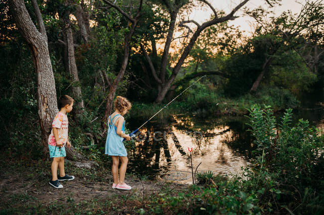 Симпатичные мальчик и девочка на озере рыбалки — стоковое фото