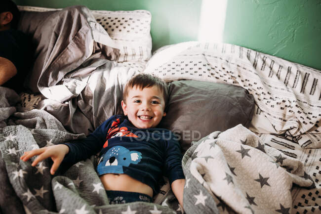 Netter Junge lächelt im Bett — Stockfoto
