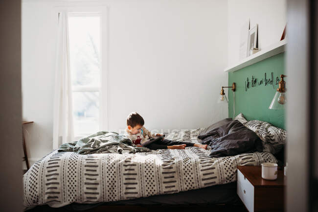 Netter Junge mit Tablet auf dem Bett — Stockfoto
