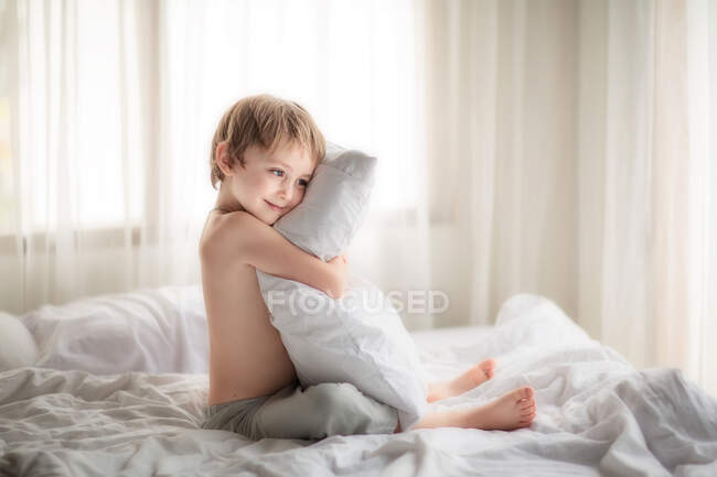 Маленький хлопчик на ліжку з подушкою — стокове фото