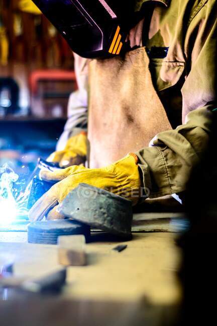 Man with yellow gloves welding in a workshop. — Stock Photo