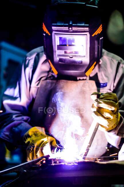 Mann schweißt in Werkstatt mit gelben Handschuhen und schwarzer Maske — Stockfoto