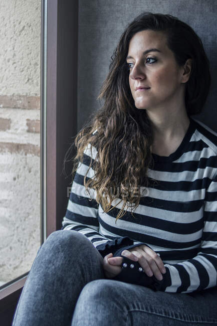Una giovane ragazza sta riposando seduta vicino ad una finestra — Foto stock