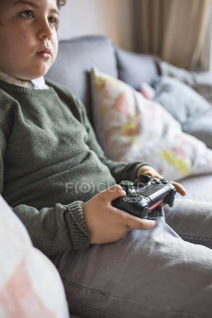Niño jugando videojuegos con joystick y consola - foto de stock