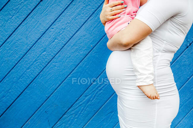 Bump shot de la mujer embarazada sosteniendo niño - foto de stock