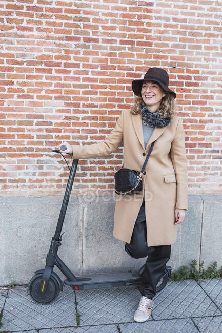 Beautiful young lady with scooter on the street — Stock Photo