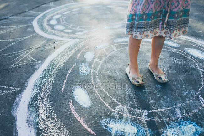 Little girl standing inside of her chalk drawings — Stock Photo