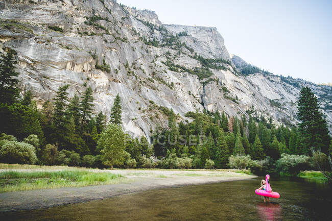 Wide shot of girl in flamingo floatie in Yosemite setting — Stock Photo
